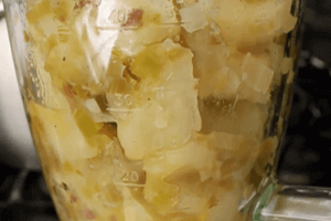 Перекладіть скибочки картоплі і трохи зеленого часнику в блендер з приблизно 1/2 склянки бульйону з каструлі.